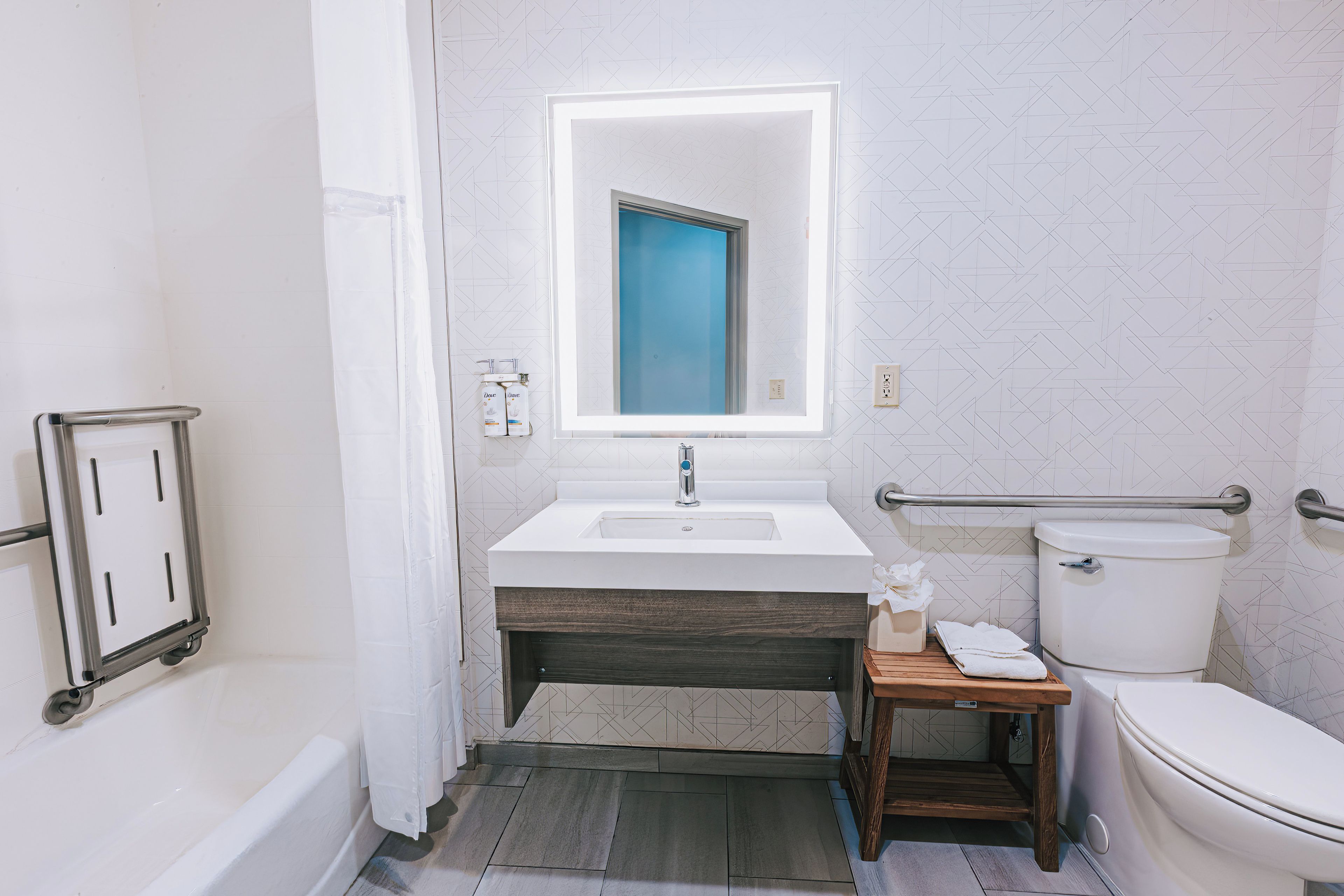 A bathroom with a white sink, a mirror, a toilet, and a shower area.