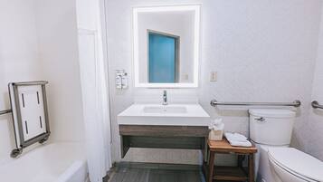 A bathroom with a white sink, a mirror, a toilet, and a shower area.