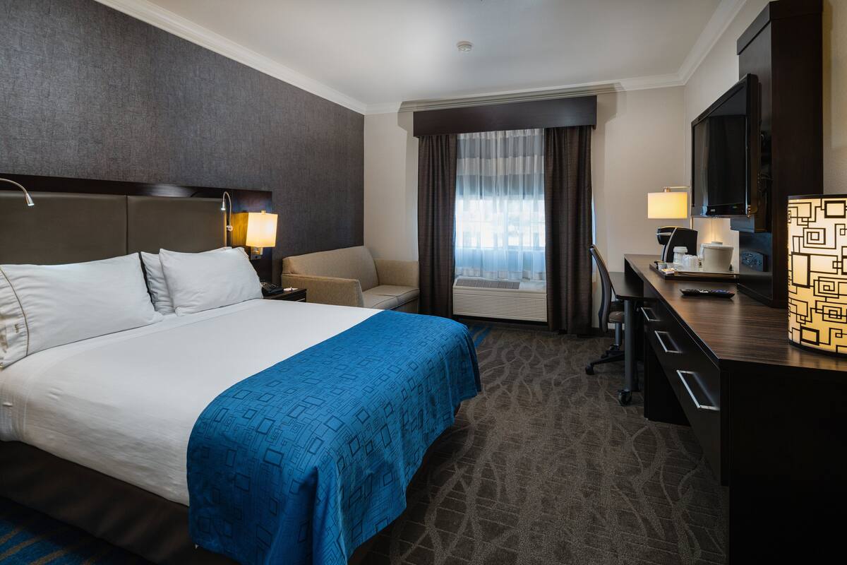 Une chambre d’hôtel avec un grand lit, un bureau avec un ordinateur, une chaise et un téléviseur.
