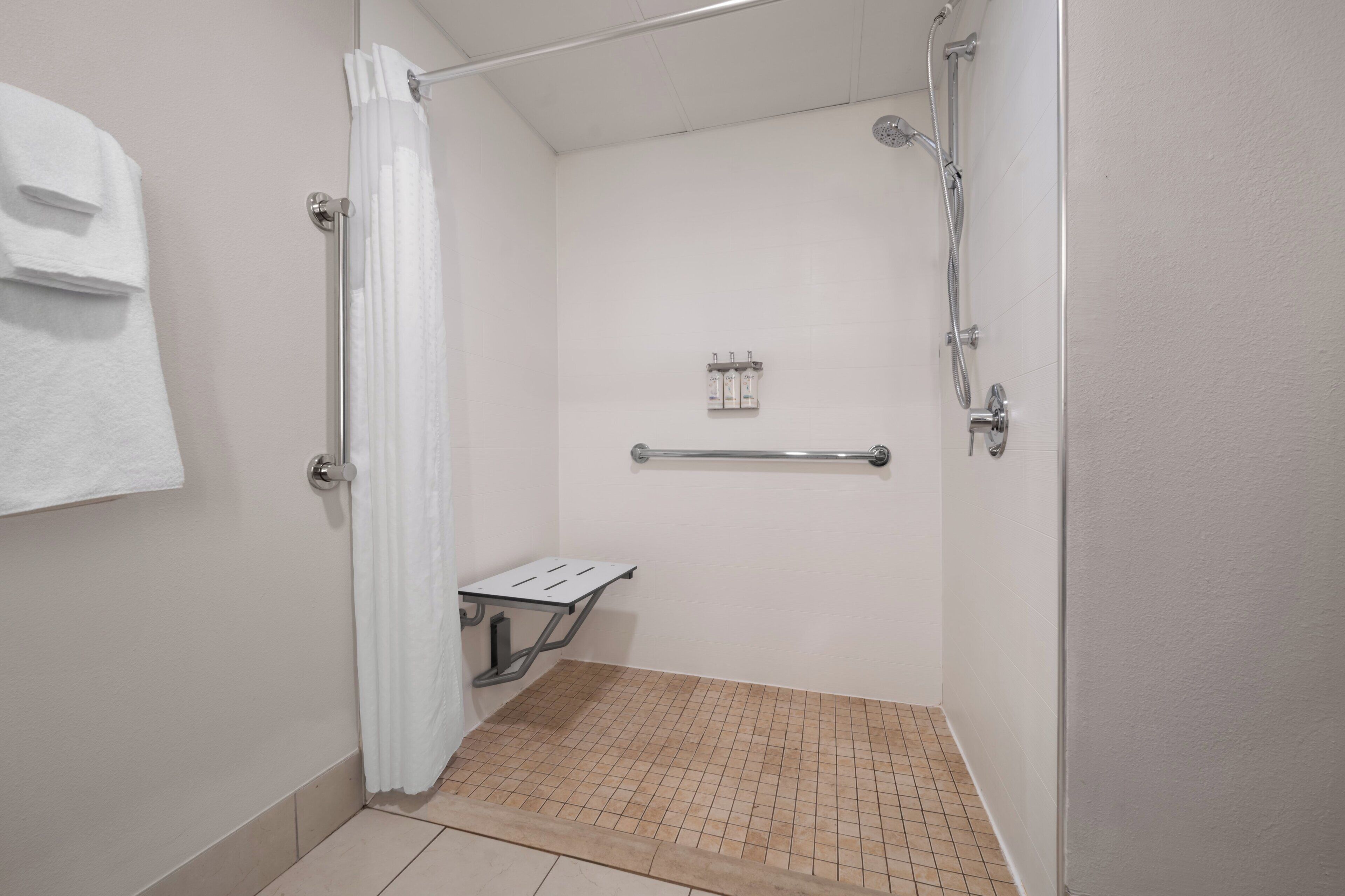 A small, enclosed shower area with a showerhead, a grab bar, and a towel rack.