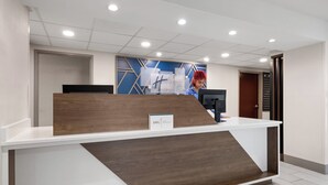 A reception desk with a modern design, a blue accent wall, and a digital screen. - Holiday Inn Exp Winston Salem by IHG (Winston-Salem)