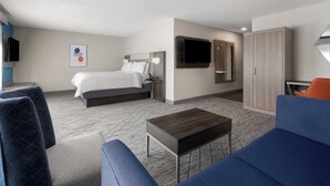 A modern hotel room with a bed, a TV, a wardrobe, and a seating area. - Holiday Inn Exp Winston Salem by IHG (Winston-Salem)
