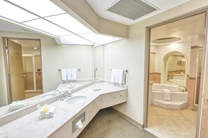 A modern bathroom with a large mirror, two sinks, a shower, and a bathtub.