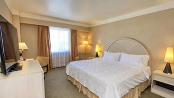 Habitación de hotel con una cama grande, dos lámparas de noche, un escritorio con computadora y una silla.