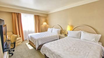 Habitación de hotel con dos camas, un escritorio, una silla y un televisor.