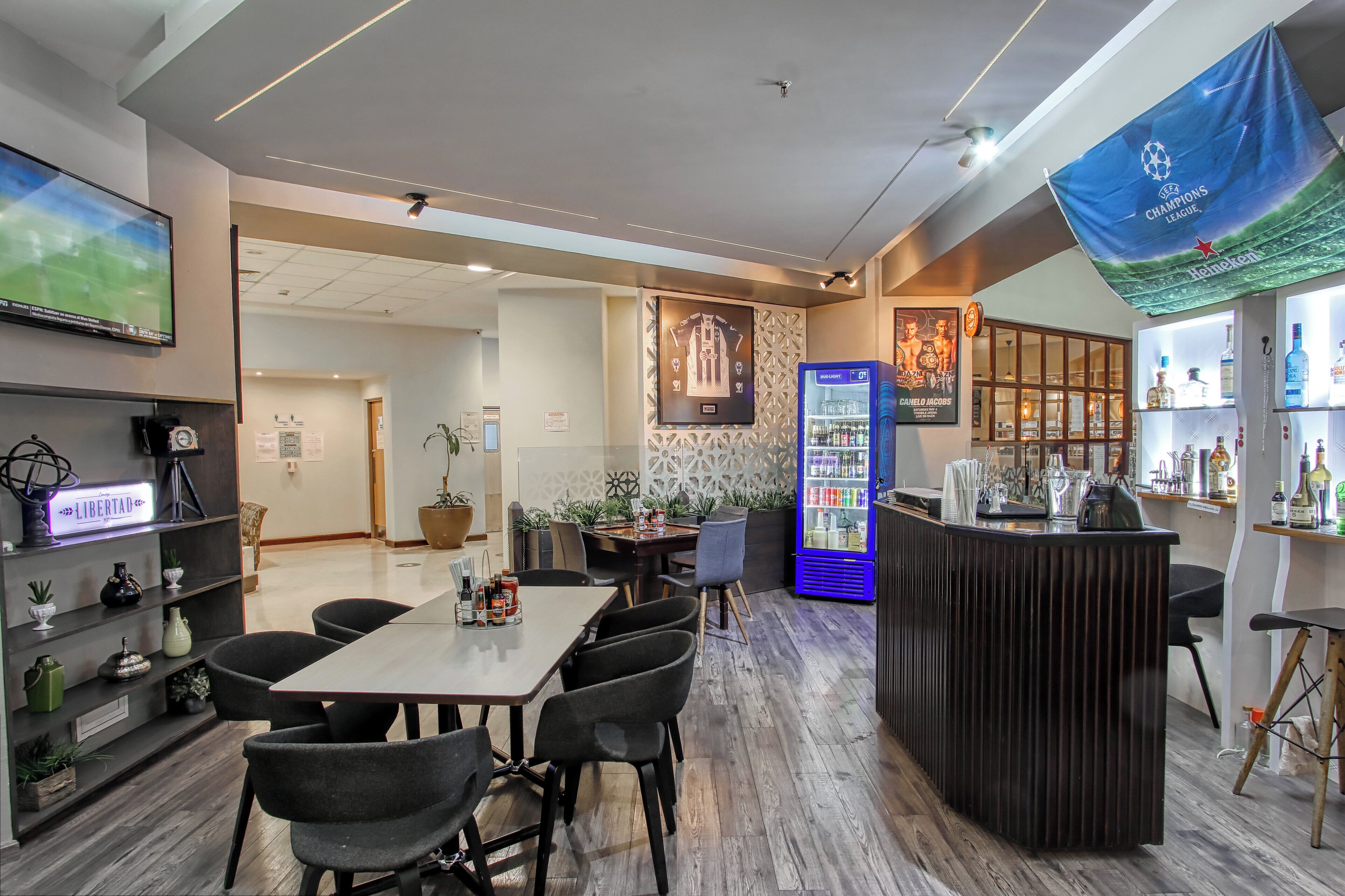 A modern restaurant with a bar area, a large screen, and a Heineken banner.