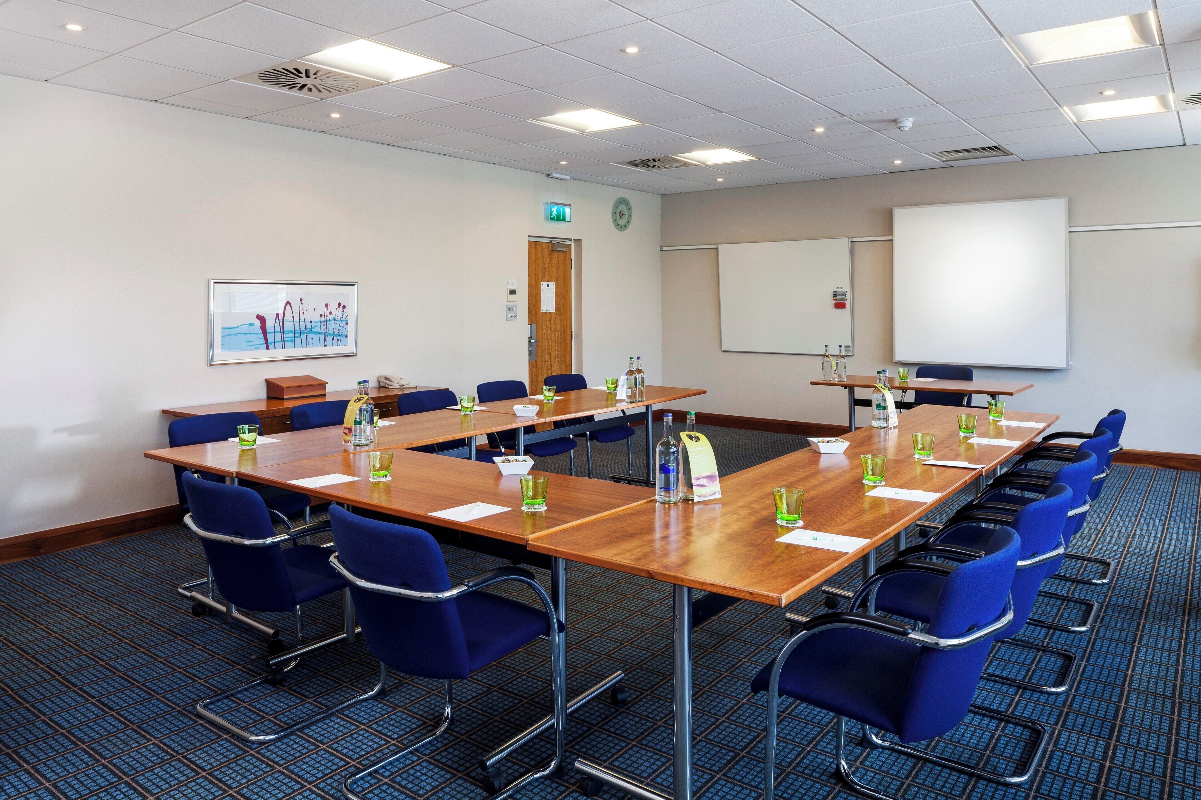 A conference room with a long table, blue chairs, and a whiteboard.