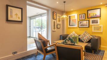A hotel room with a dining area, a sofa, and a large window.