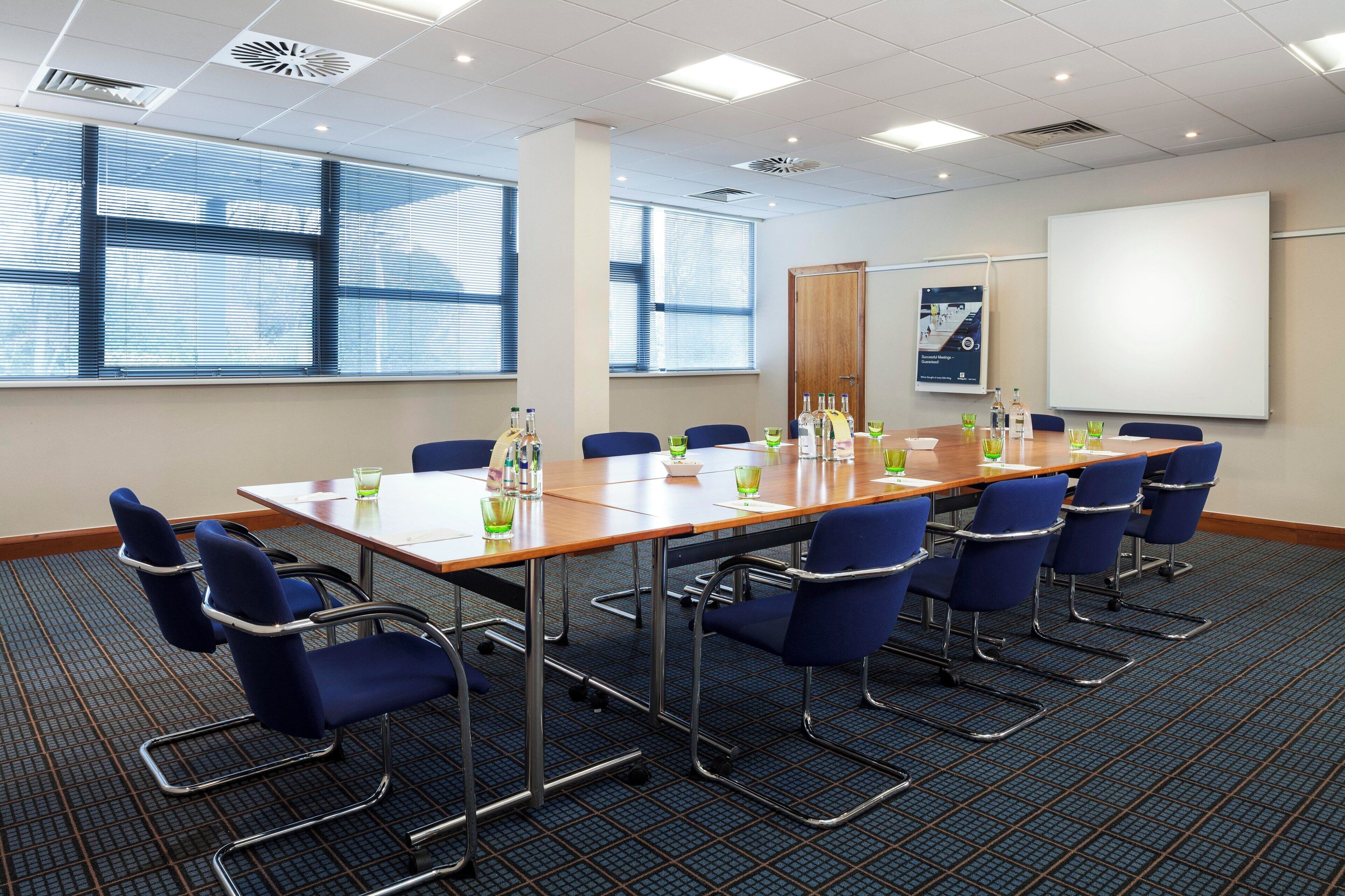 A conference room with a long table, blue chairs, and a whiteboard.
