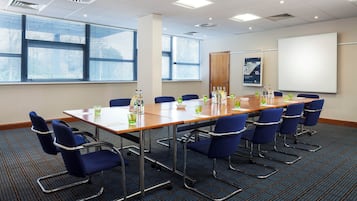 A conference room with a long table, blue chairs, and a whiteboard.