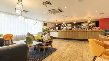 A hotel lobby with a reception desk, seating area, and bar.