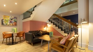 A modern living room with a staircase, a sofa, a coffee table, and a dining area.