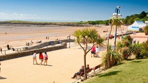A beach with a sandy shore, a stone wall, and a few people walking.