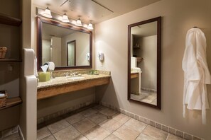 Un baño con tocador de madera, un espejo grande y un perchero para toallas.