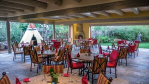 An outdoor dining area with tables and chairs, a teepee, and a stone fireplace. - The Hacienda & Spa at Hotel Santa Fe (Santa Fe)