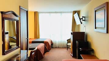 A hotel room with two beds, a desk, a chair, a TV, and a window with curtains.