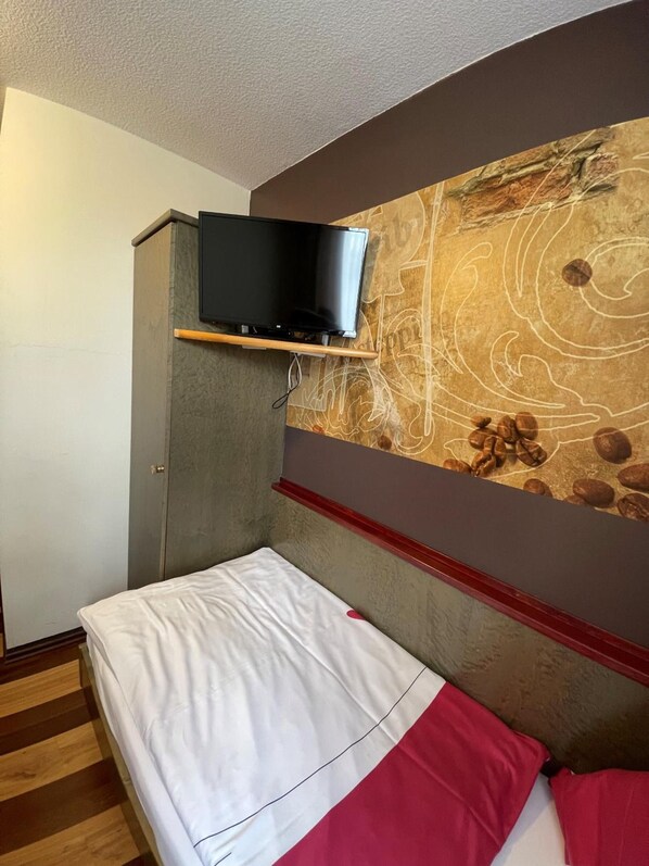 A hotel room with a bed, a television mounted on a cabinet, and a wall with a geological map design.