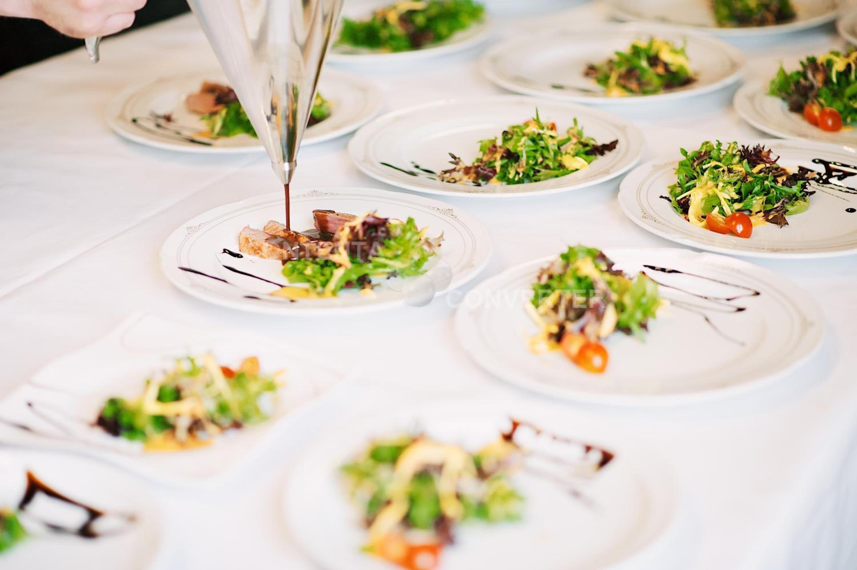 A table with multiple plates of food, each garnished with green leaves and a cherry tomato.