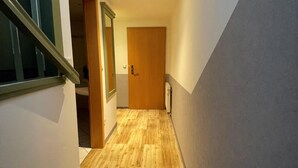 A staircase leading to a wooden door at the end of a hallway with a light fixture above. - Bebras Hessischer Hof (Bebra)