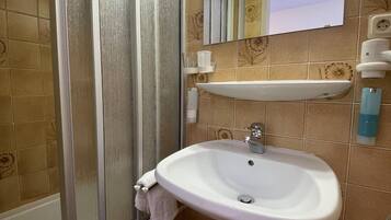 Un baño con lavamanos blanco, espejo, ducha e inodoro.
