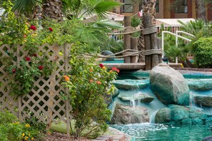 A garden with a wooden fence, a small waterfall, and a pool. - Westgate Flamingo Bay Resort (Las Vegas)