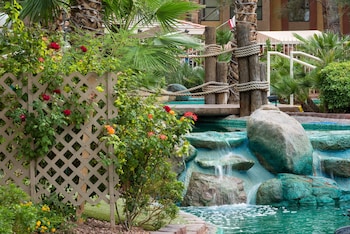 A hotel with a swimming pool, palm trees, and a fountain. at Westgate Flamingo Bay Resort