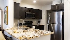 A modern kitchen with dark cabinets, stainless steel appliances, and a marble countertop. - Westgate Flamingo Bay Resort (Las Vegas)