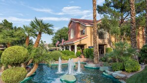 A hotel with a swimming pool, palm trees, and a fountain. - Westgate Flamingo Bay Resort (Las Vegas)