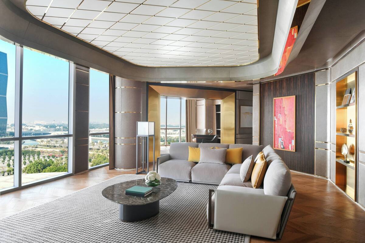 A modern living room with a large window, a sofa, a coffee table, and a lamp.