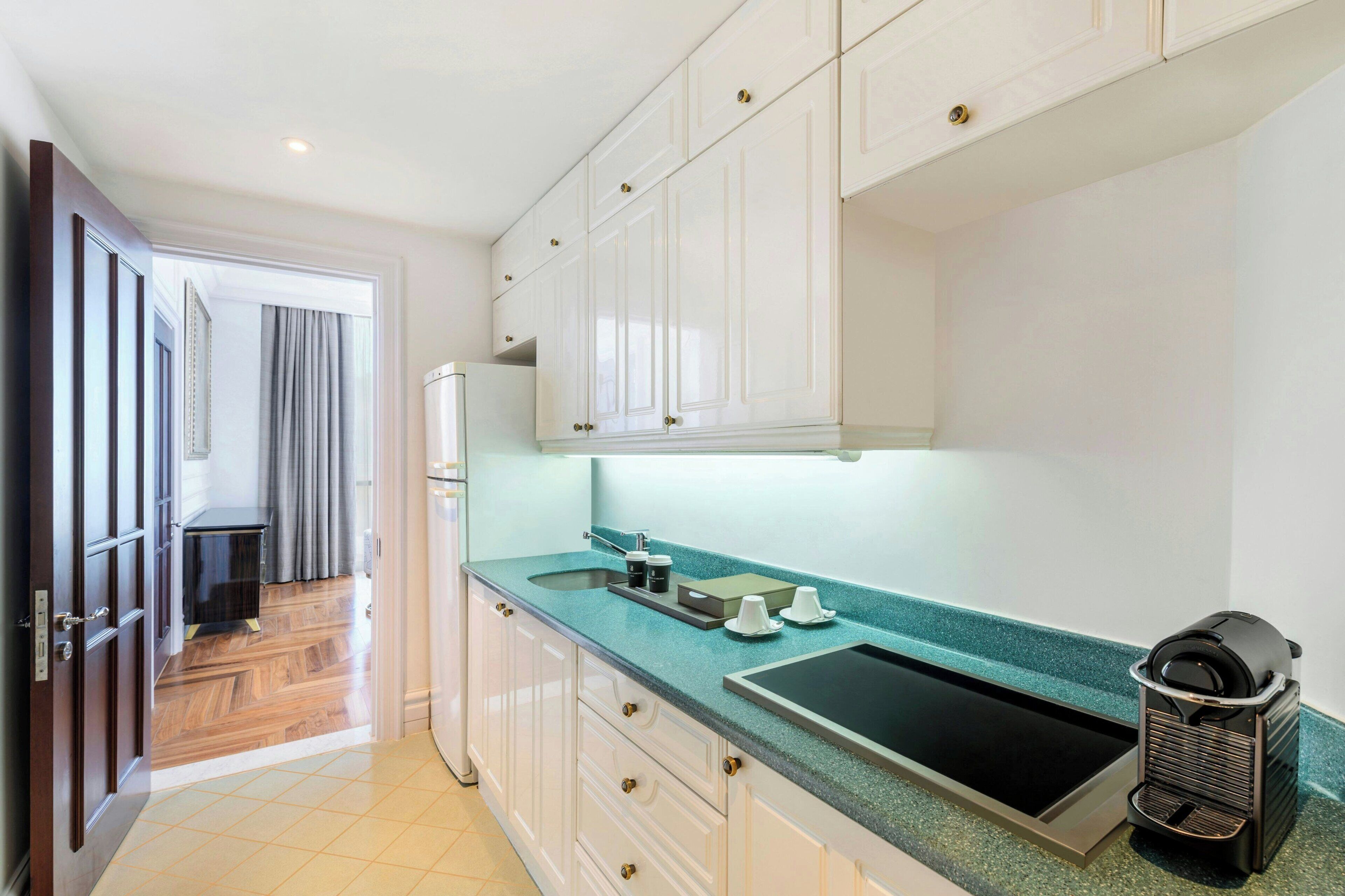 A modern kitchen with white cabinets, a teal countertop, and a built-in oven.