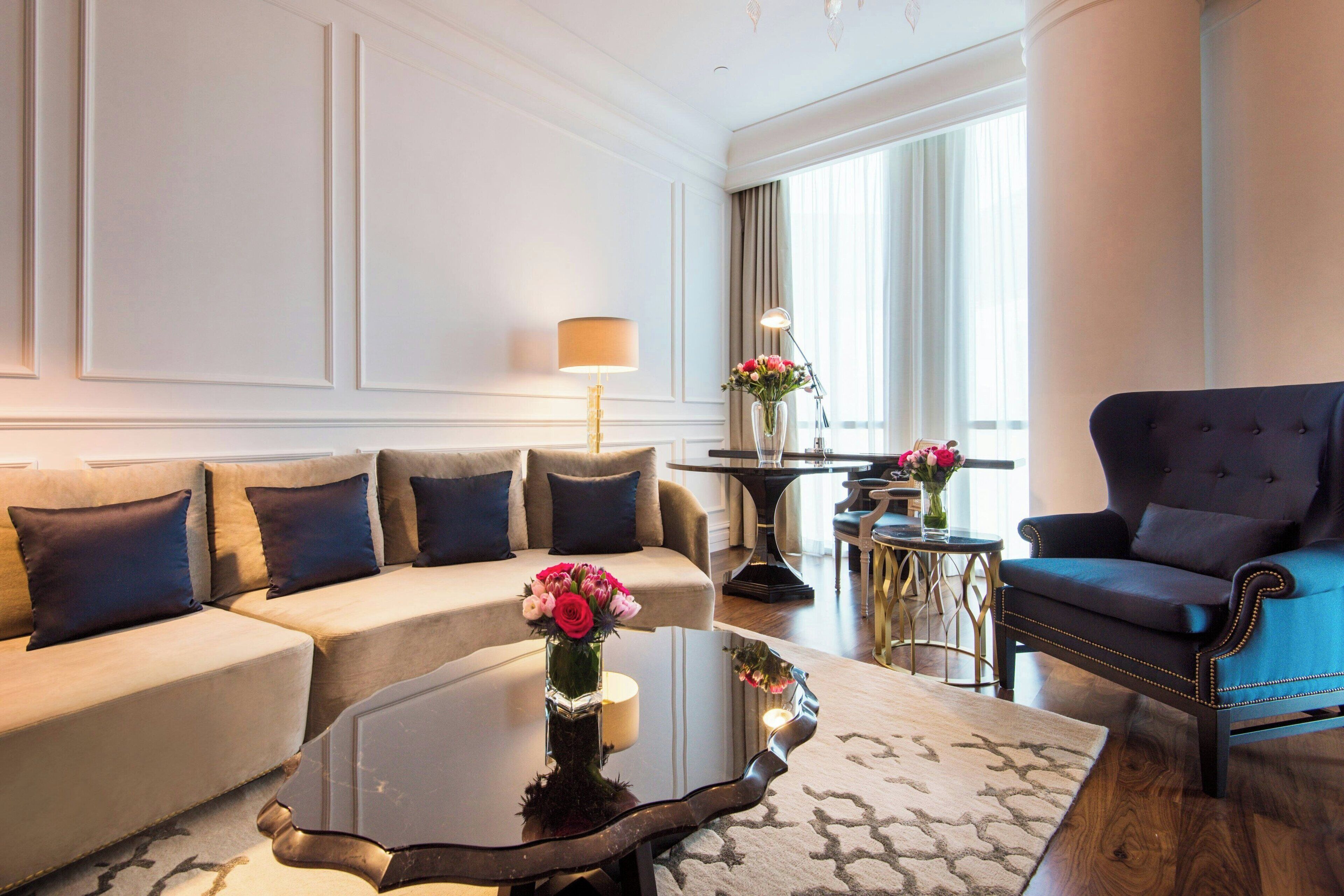 A modern living room with a sofa, armchair, coffee table, and a vase of flowers.