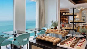 Un comedor con vista al océano, un bufé con diversos pasteles y un diseño de interiores moderno.