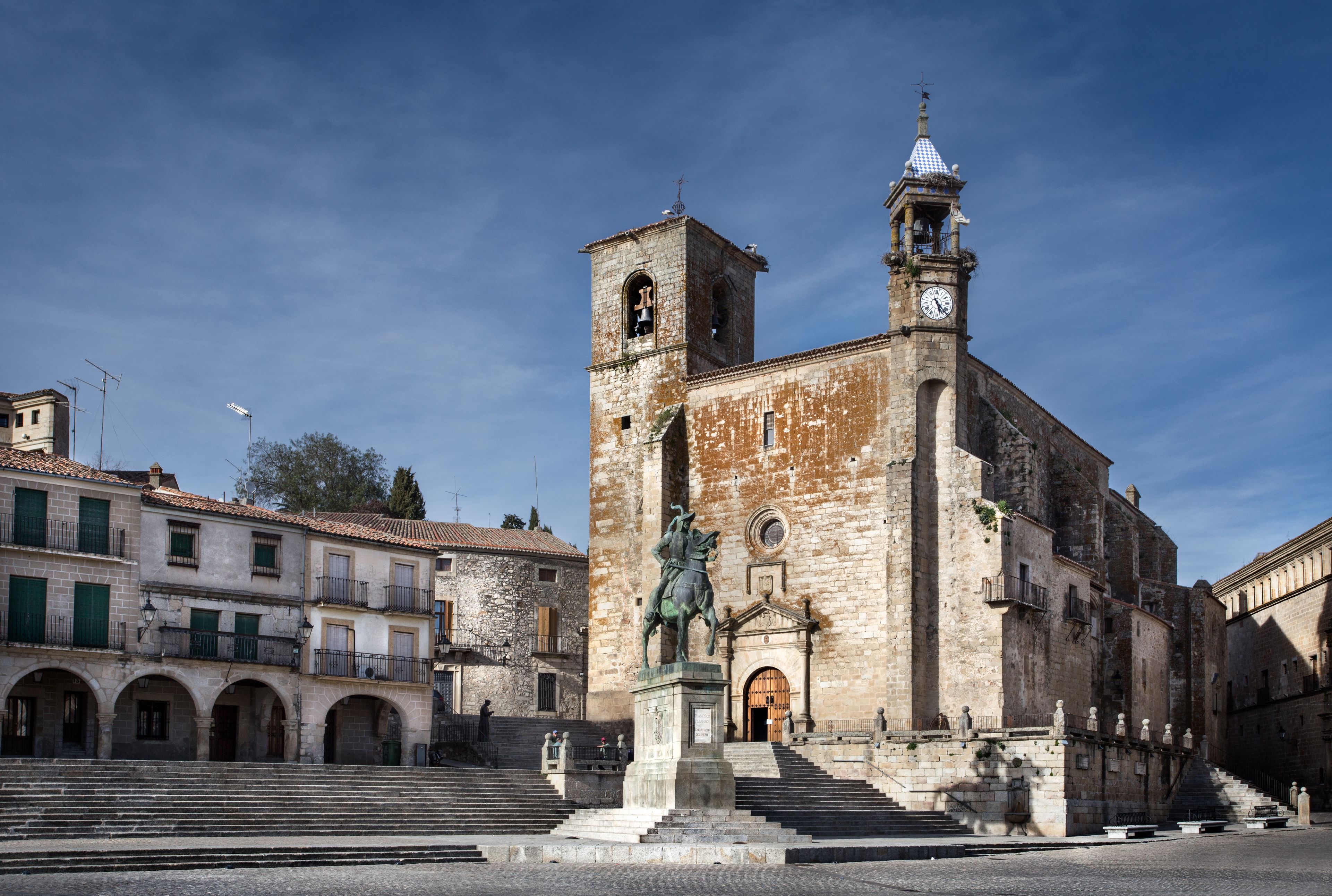 Una iglesia histórica con un campanario y una estatua en primer plano.