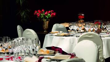 Una elegante disposición para el comedor con varias mesas, sillas y un jarrón de rosas rojas.
