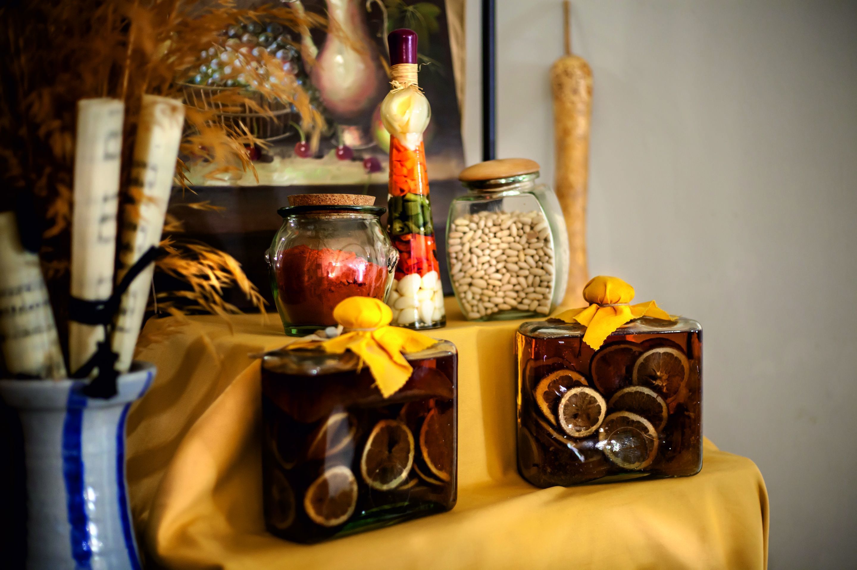 Une table sur laquelle se trouvent des bocaux contenant des fruits et des légumes conservés, une cuillère en bois et un vase décoratif.