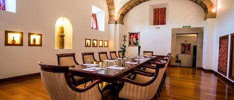 A conference room with a long table, chairs, and framed pictures on the walls.