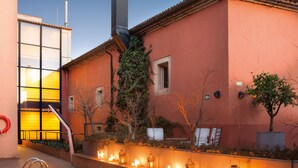 Un área de piscina con terraza de baldosas, sillas de descanso y una mesa con velas.