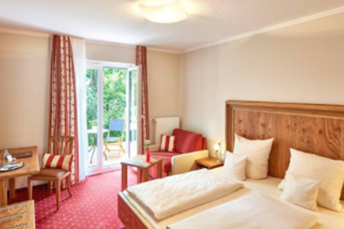 Habitación de hotel con cama, escritorio, silla y vistas al exterior.