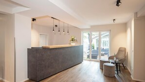 A modern kitchen with a central island, pendant lights, and a view to the outside. - Hotel Langwieder See (Munich)