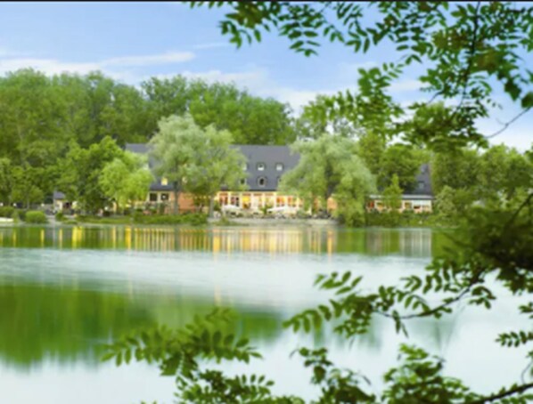 A lakeside hotel with a calm lake reflecting the buildings. - Hotel Langwieder See (Munich)