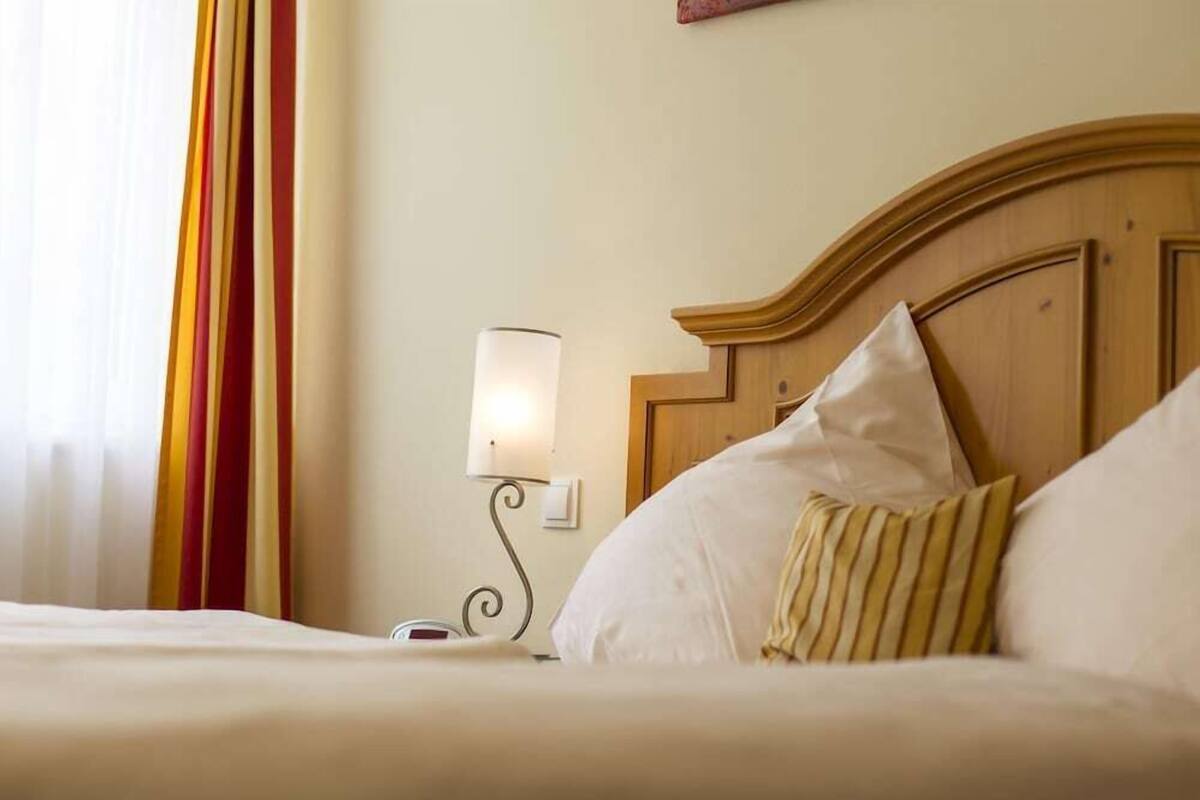 Una habitación de hotel con cabecera de madera, lámpara de noche y cortinas a rayas.