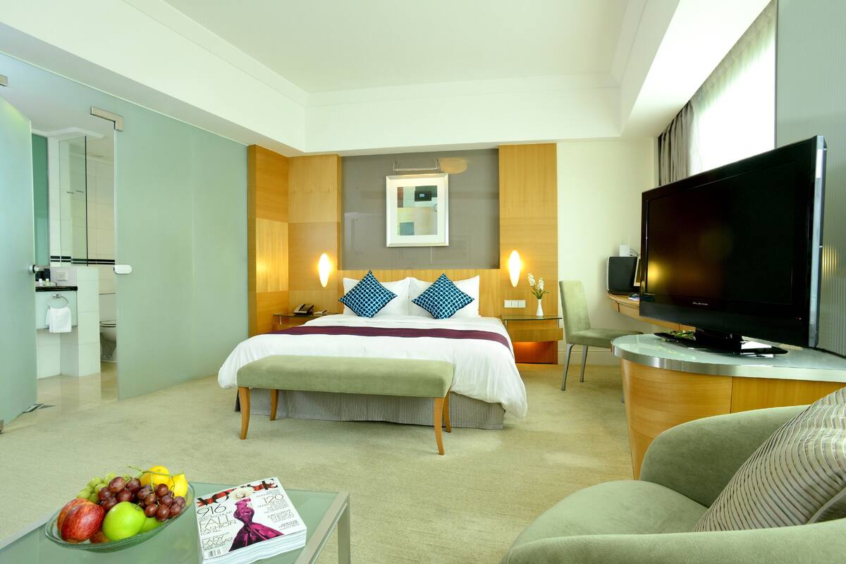Une chambre d’hôtel équipée d’un lit, d’une télévision, d’un bureau et d’un panier de fruits.
