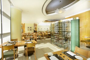 A spacious dining area with multiple tables and chairs, a glass wine rack, and a modern ceiling design. - Metropark Hotel Causeway Bay HK (Hong Kong)