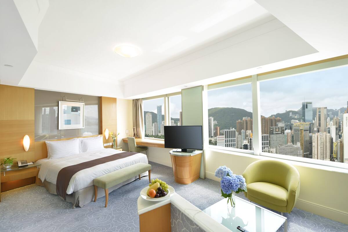 Une chambre d’h ôtel équipée d’un lit, d’un bureau, d’une télévision, d’une table basse et offrant une vue sur la ville.