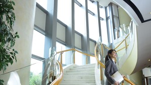 Een marmeren trap met glazen balustrades en een gebogen ontwerp, leidend naar een verdieping.