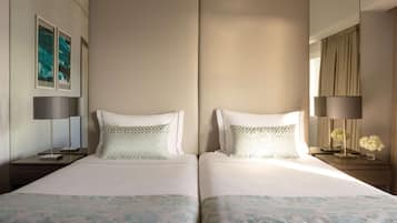 Habitación de hotel con dos camas, una mesita de noche con lámpara, un espejo y obras de arte en la pared.