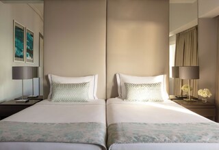 A hotel room with two beds, a large mirror, and a nightstand with a lamp.