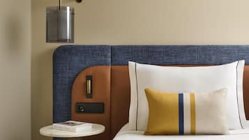 A neatly arranged hotel room with a bed, a bedside table with a book, and a wall-mounted lamp.