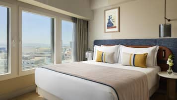 Habitación de hotel con una cama grande, vistas de la ciudad y un cuadro en la pared.