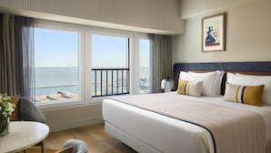 Habitación de hotel con una cama grande, vistas al mar, una mesa de comedor y una silla.